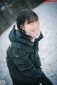 A woman wearing a black jacket standing in the snow.