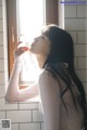 A woman drinking water from a bottle in a bathroom.