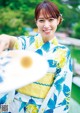 A woman in a blue and yellow kimono holding a fan.