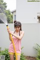 A woman in a pink tank top and yellow shorts holding a yellow hose.