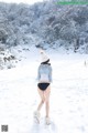 A woman walking in the snow wearing a hat and boots.